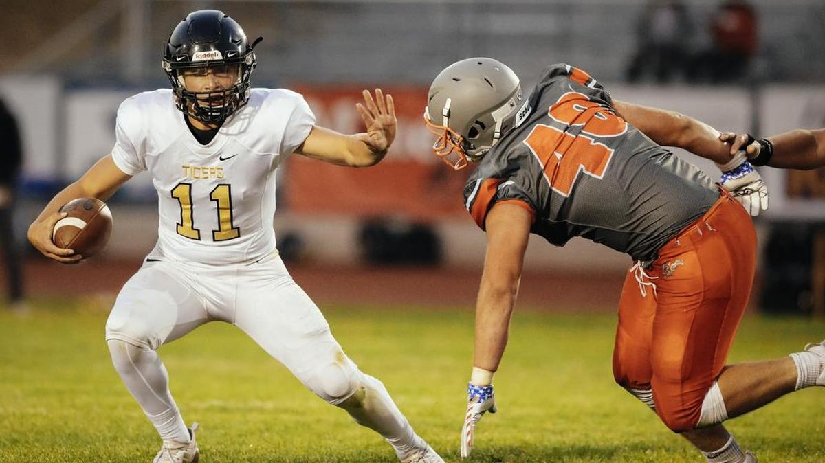 San Luis Obispo High School quarterback Emilio Corona fends off an Atascadero defender in SLO High’s 21-14 non-conference win Friday night in Atascadero, California.
