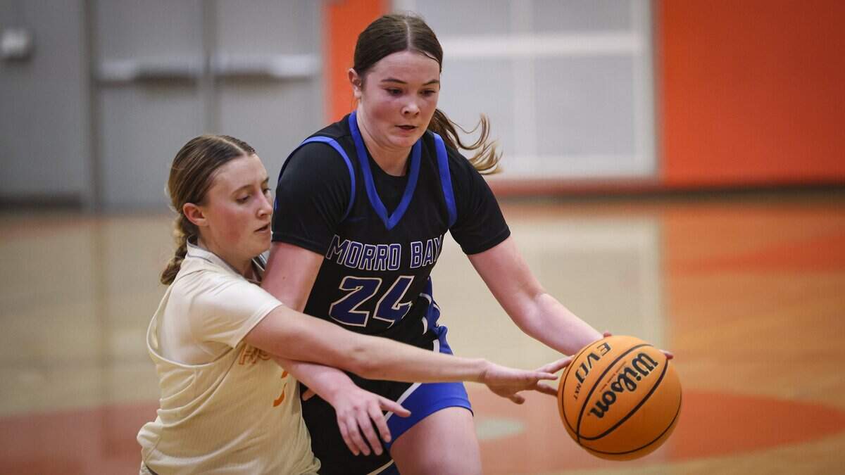 Laney Arnold reaches defending against Violet Pace. Morro Bay girls basketball team beat Atascadero 52-36 on Jan. 13, 2026.