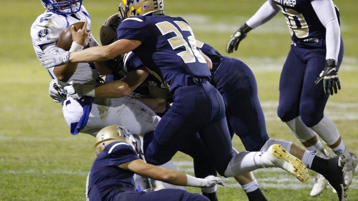 Mission Prep’s defense gangs up to tackle Morro Bay quarterback Isaac Manuputy in Friday night’s game.