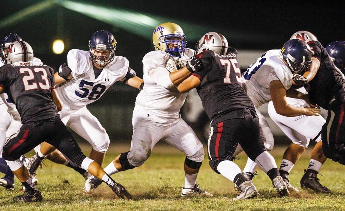 Danny Shiraishi, center, goes up against Nipomo’s defense wearing a borrowed helmet from Allan Hancock College after a crack was found in his normal helmet.
