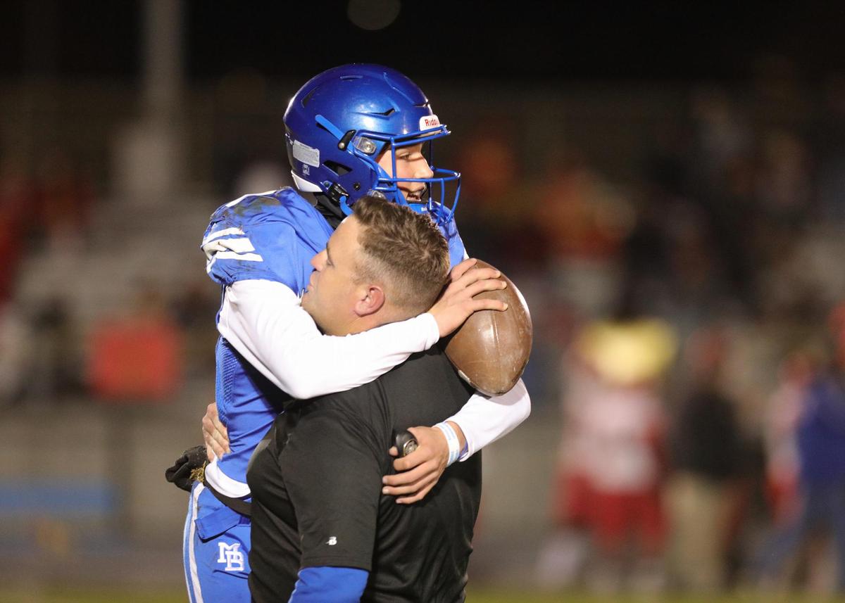 Quarterback Nicky Johnson hugs coach Jake Goosen-Brown after Morro Bay defeated Loara High of Anaheim 35-27 in a state playoff game, Dec. 3, 2021.