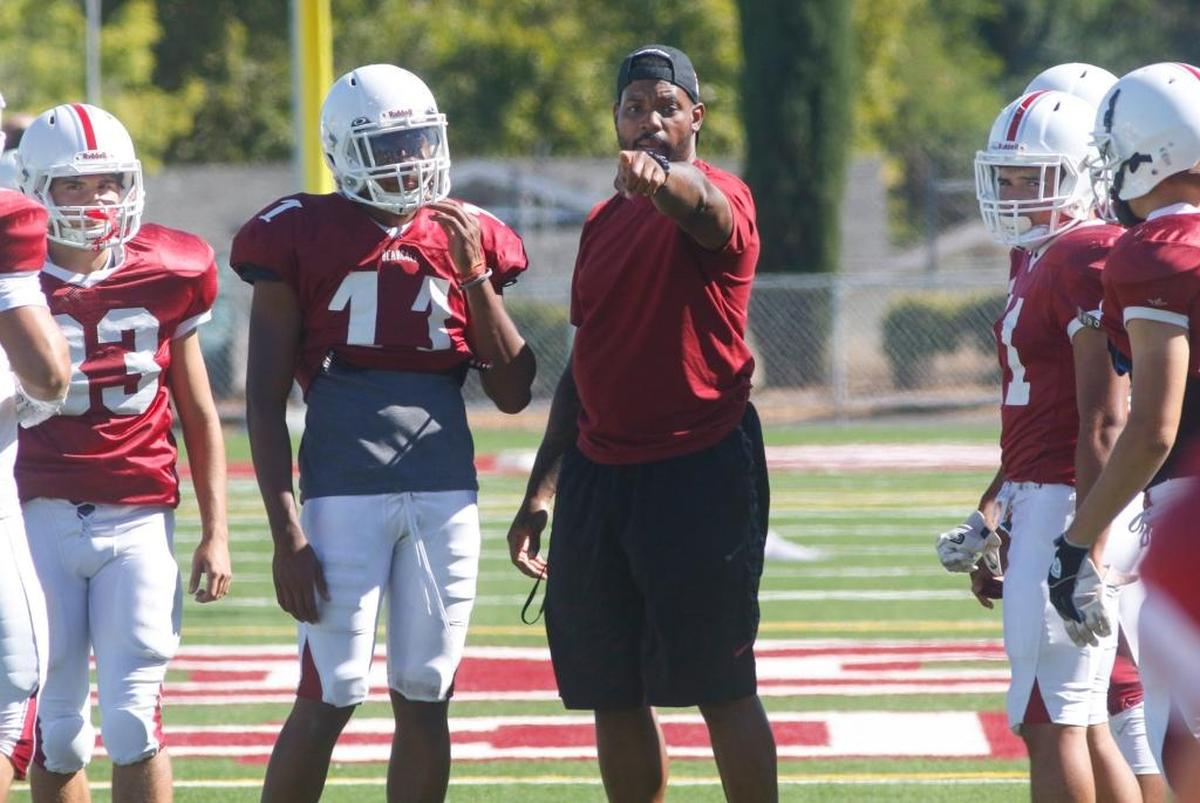 Paso Robles High senior Sincere Jackson (11) stands next to former head football coach Larry Grant during a preseason practice. 8-14-2017