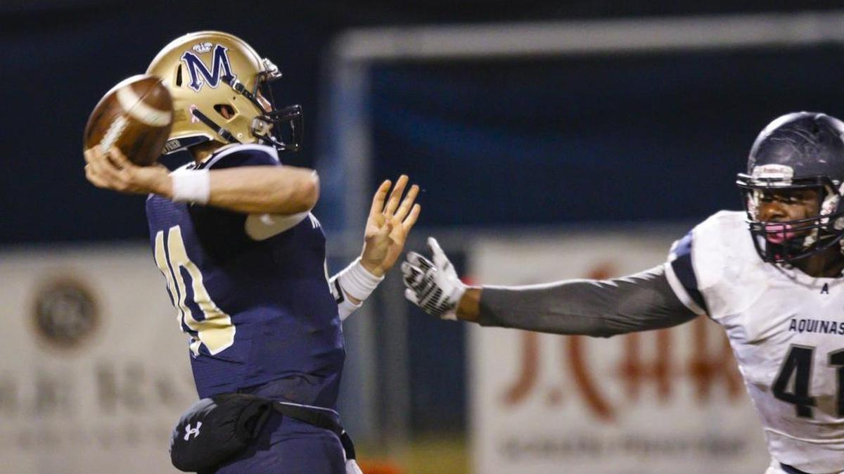 Bryce Fledderman of Mission Prep throws a pass under pressure from Aquinas defensive end Christian Boucher in the second half of Friday night’s playoff game.