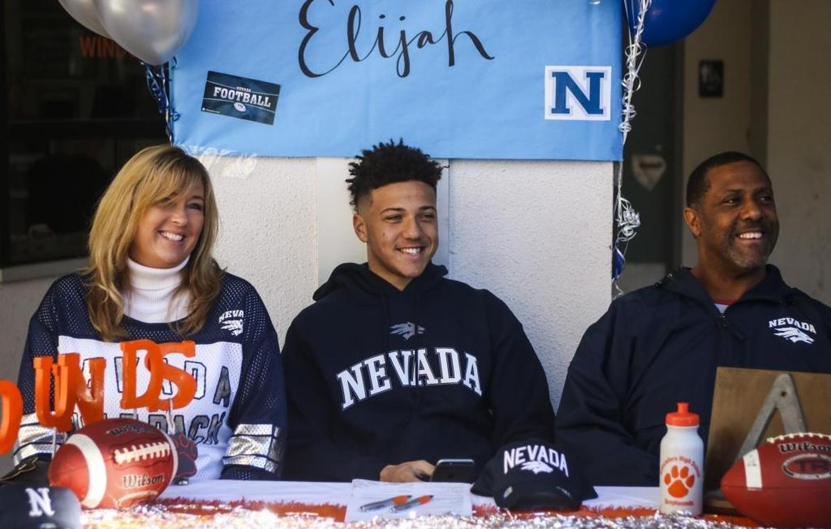 Atascadero senior Elijah Cooks (center) surrounded by his mother Stephanie Cooks and father Adrian Cooks as he signs his National Letter of Intent to play football at Nevada last year.