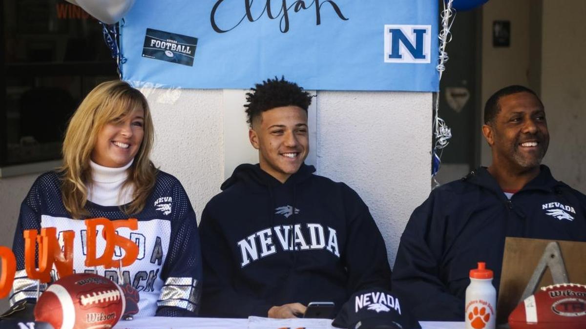 Atascadero senior Elijah Cooks (center) surrounded by his mother Stephanie Cooks and father Adrian Cooks as he signs his National Letter of Intent to play football at Nevada last year.