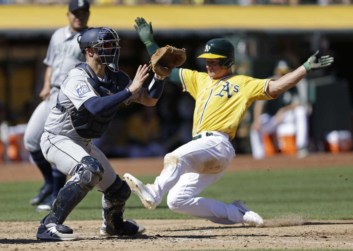 Oakland Athletics’ Matt Chapman slides to score as Seattle Mariners catcher Mike Marjama, left, waits for the ball in the fourth inning of a baseball game Wednesday, Sept. 27, 2017, in Oakland, Calif. Chapman scored on a sacrifice fly from A’s Mark Canha. (AP Photo/Ben Margot)