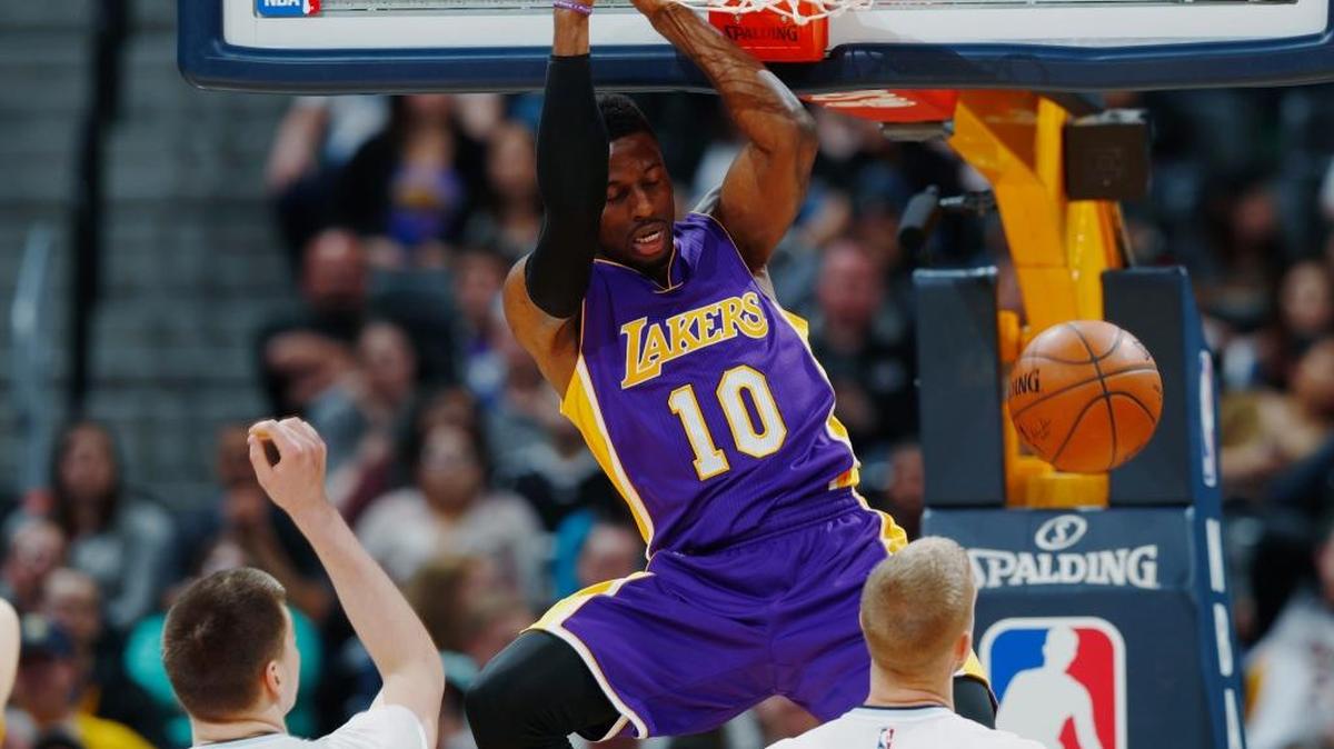 Los Angeles Lakers guard David Nwaba, a former Cal Poly standout, hangs on the rim after dunking the ball over Denver Nuggets forward Nikola Jokic, front left, and center Mason Plumlee in the second half of an NBA basketball game last week in Denver.