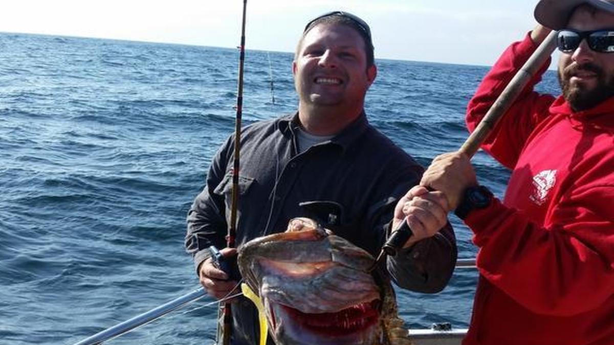 Bakersfield angler Matt Kennedy, left, shows off his catch of a 32.5-pound lingcod caught Sunday aboard Virg’s Landing vessel Rita G. Deckhand Matt Oliver, right, assists.